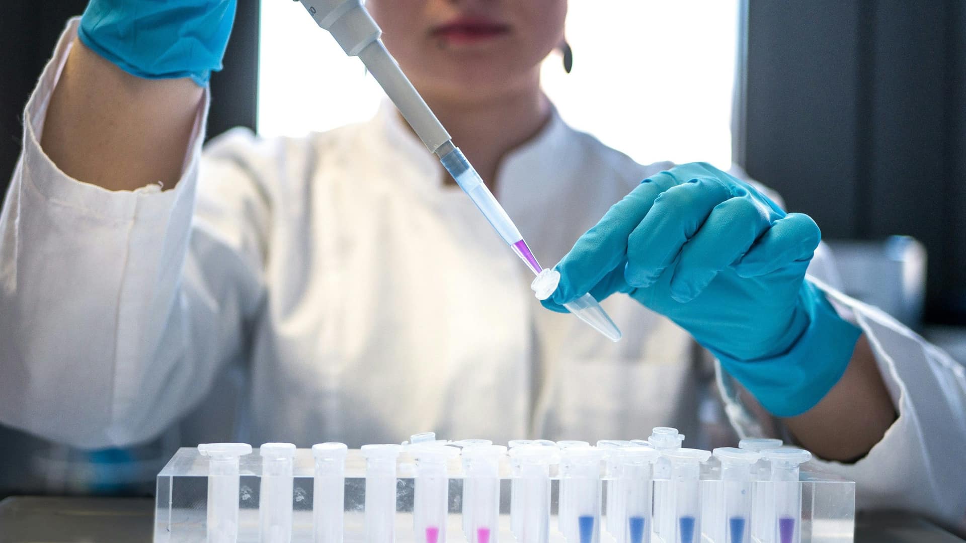 Scientifique en laboratoire manipulant une pipette au-dessus d'éprouvettes